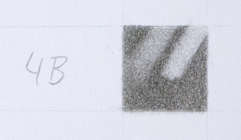 Two erasures on a swatch of 4B applied with moderate pressure. Kneaded eraser on the left, a Tombow Mono Zero stick eraser on the right.